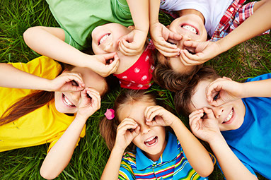 5 Kinder liegen auf einer Wiese und freuen sich